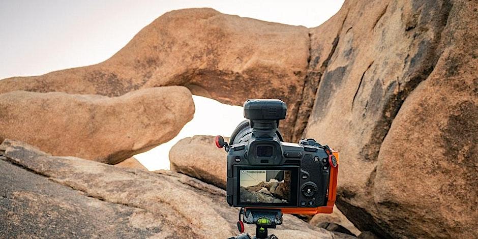 Camera on a tripod capturing a photograph of Arch Rock in Joshua Tree National Park. Picture by Jon Norris