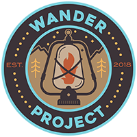 Wander Project Logo - a lantern in front of a landscape inside a circle that says "Wander Project: EST 2018"